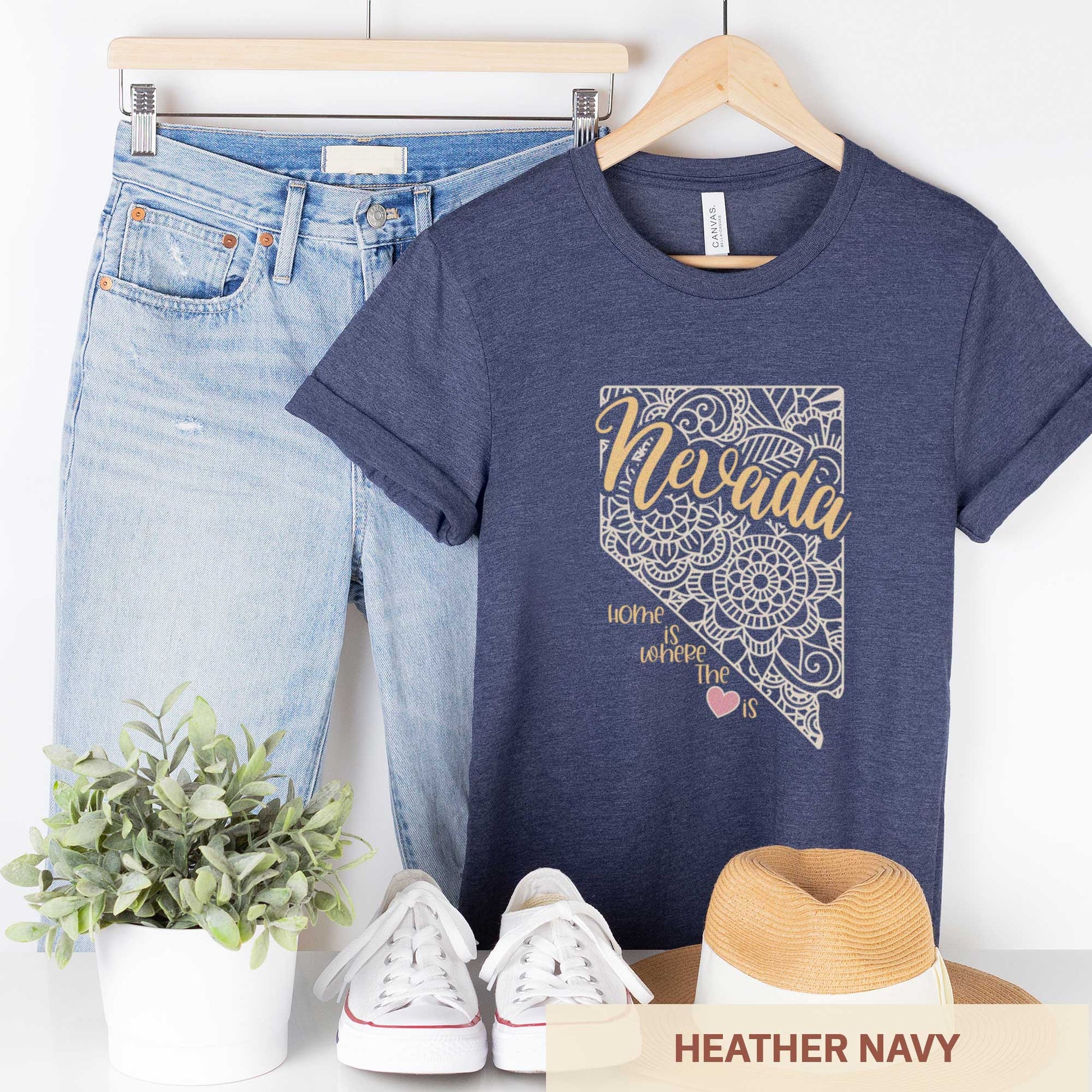 A hanging heather navy Bella Canvas t-shirt featuring a mandala in the shape of Nevada with the words home is where the heart is.