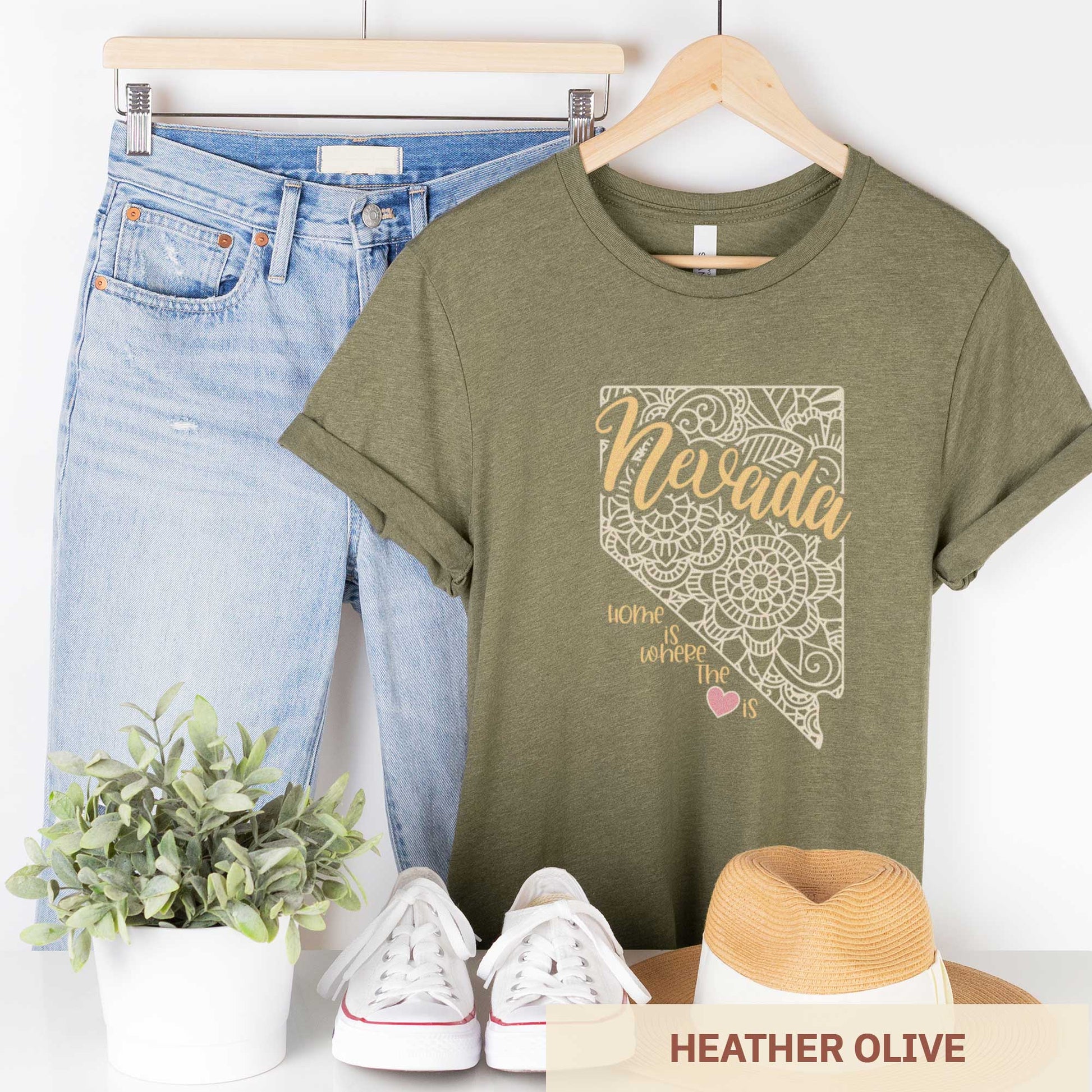 A hanging heather olive Bella Canvas t-shirt featuring a mandala in the shape of Nevada with the words home is where the heart is.