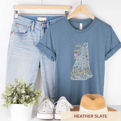 A hanging heather slate Bella Canvas t-shirt featuring a mandala in the shape of New Hampshire with the words home is where the heart is.