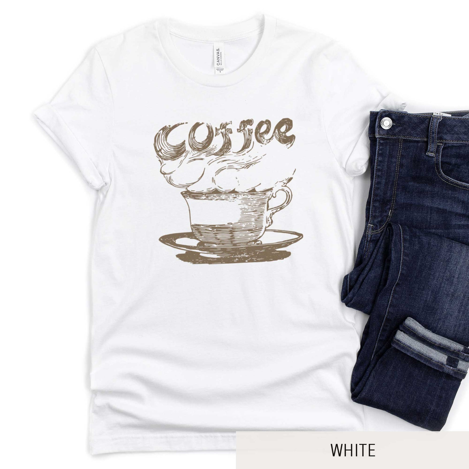 A white Bella Canvas t-shirt featuring a vintage illustration of a steaming cup of coffee with the words coffee rising out from it.