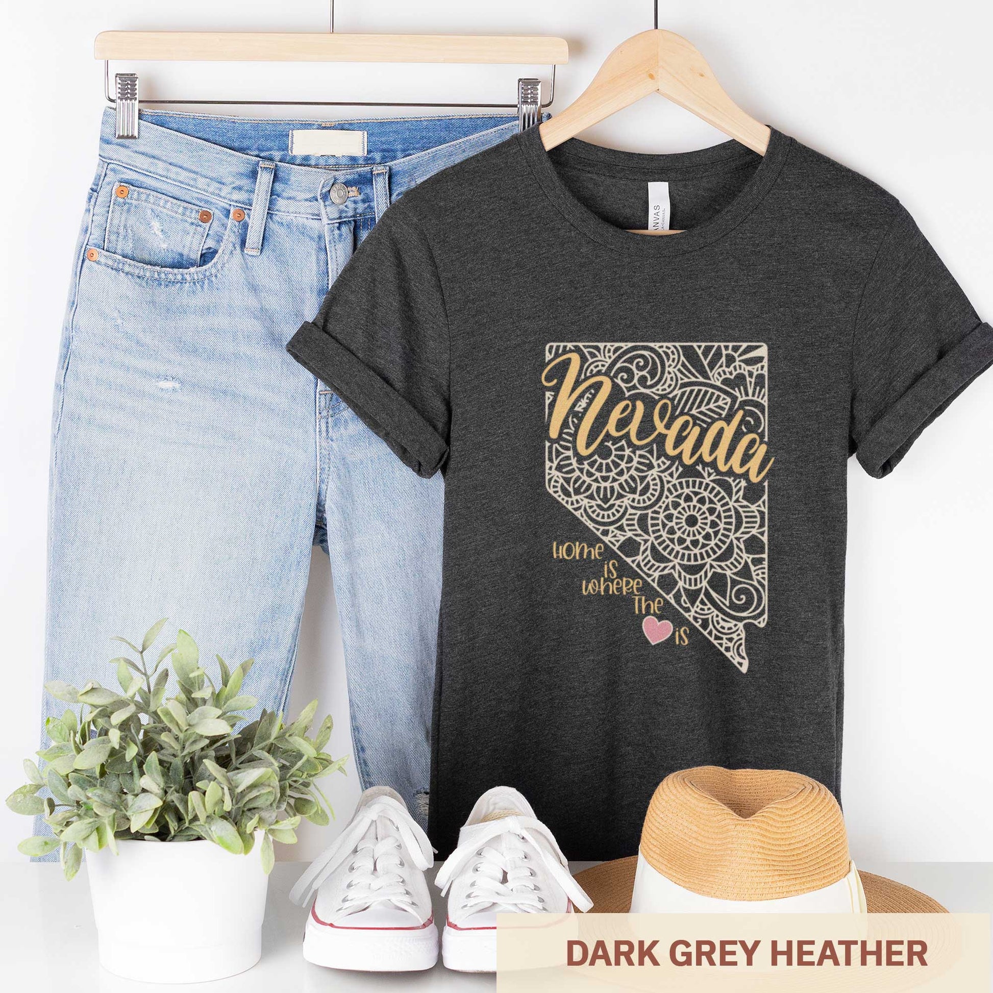 A hanging dark grey heather Bella Canvas t-shirt featuring a mandala in the shape of Nevada with the words home is where the heart is.