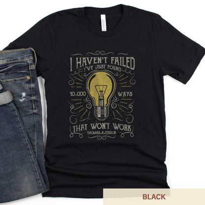 A black Bella Canvas t-shirt featuring a lightbulb in a distressed, vintage style along with the words I haven't failed I've just found 10,000 ways that wont work Thomas A. Edison.