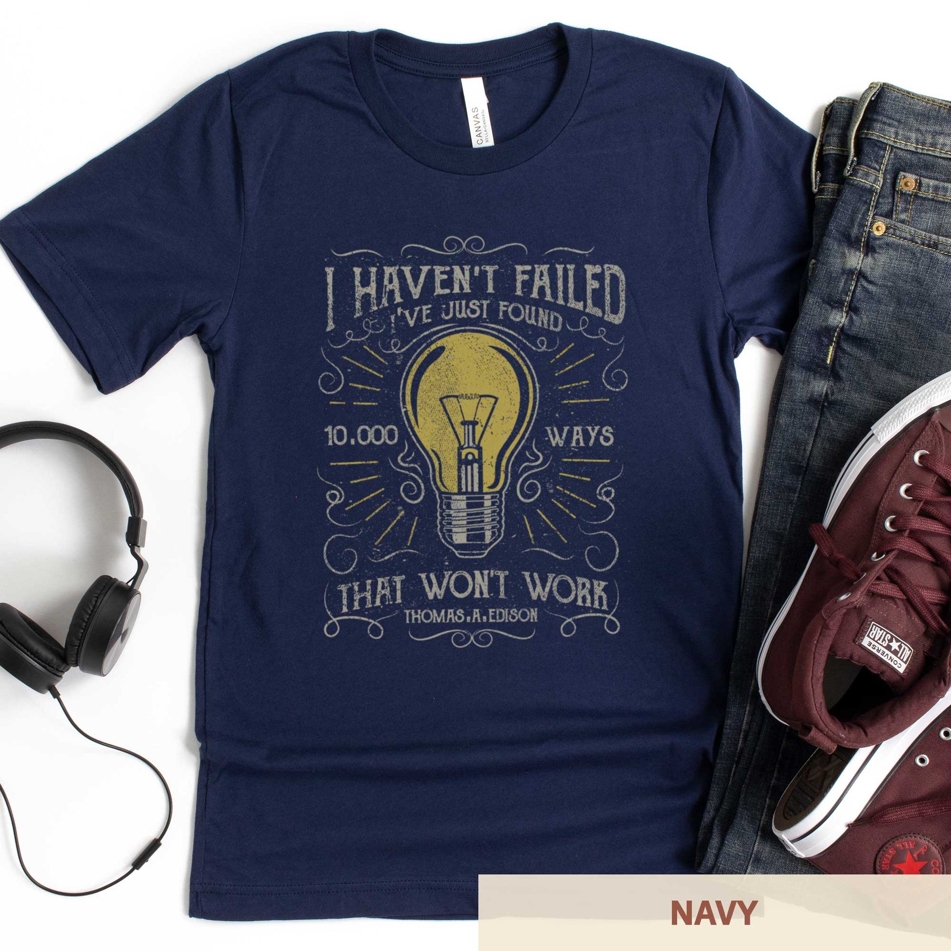 A navy Bella Canvas t-shirt featuring a lightbulb in a distressed, vintage style along with the words I haven't failed I've just found 10,000 ways that wont work Thomas A. Edison.