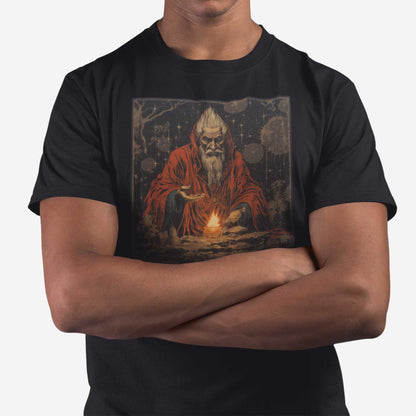 A man wearing a black Bella Canvas t-shirt featuring a medieval looking sourcerer casting a spell over a small open flame.