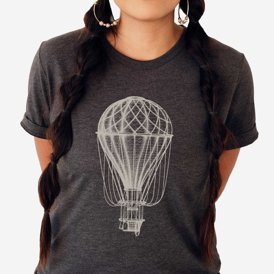 A woman wearing a dark grey heather Bella Canvas t-shirt featuring a Victorian era vintage hot air balloon.