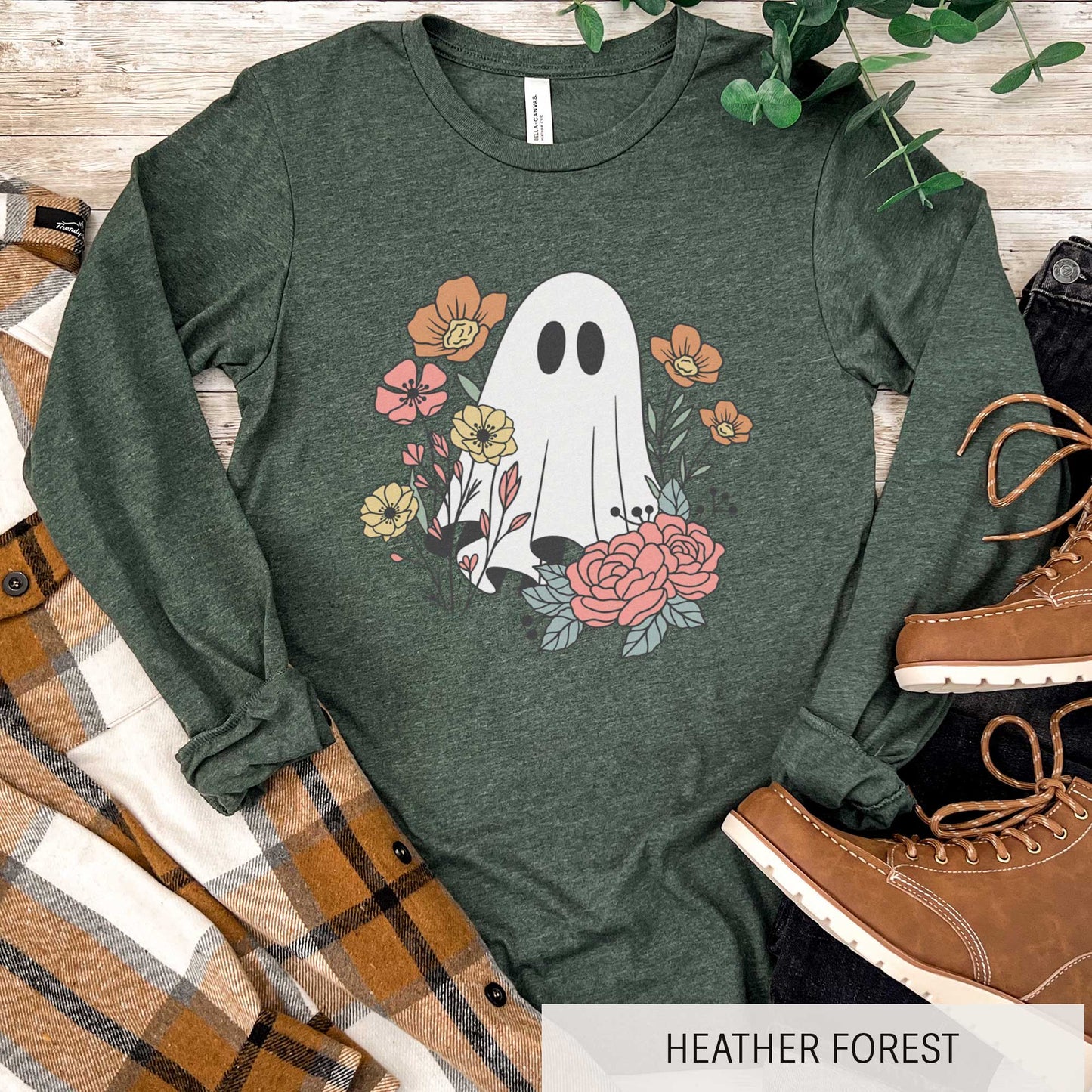 A long sleeve heather forest Bella Canvas t-shirt featuring a cartoon ghost with flowers around it.