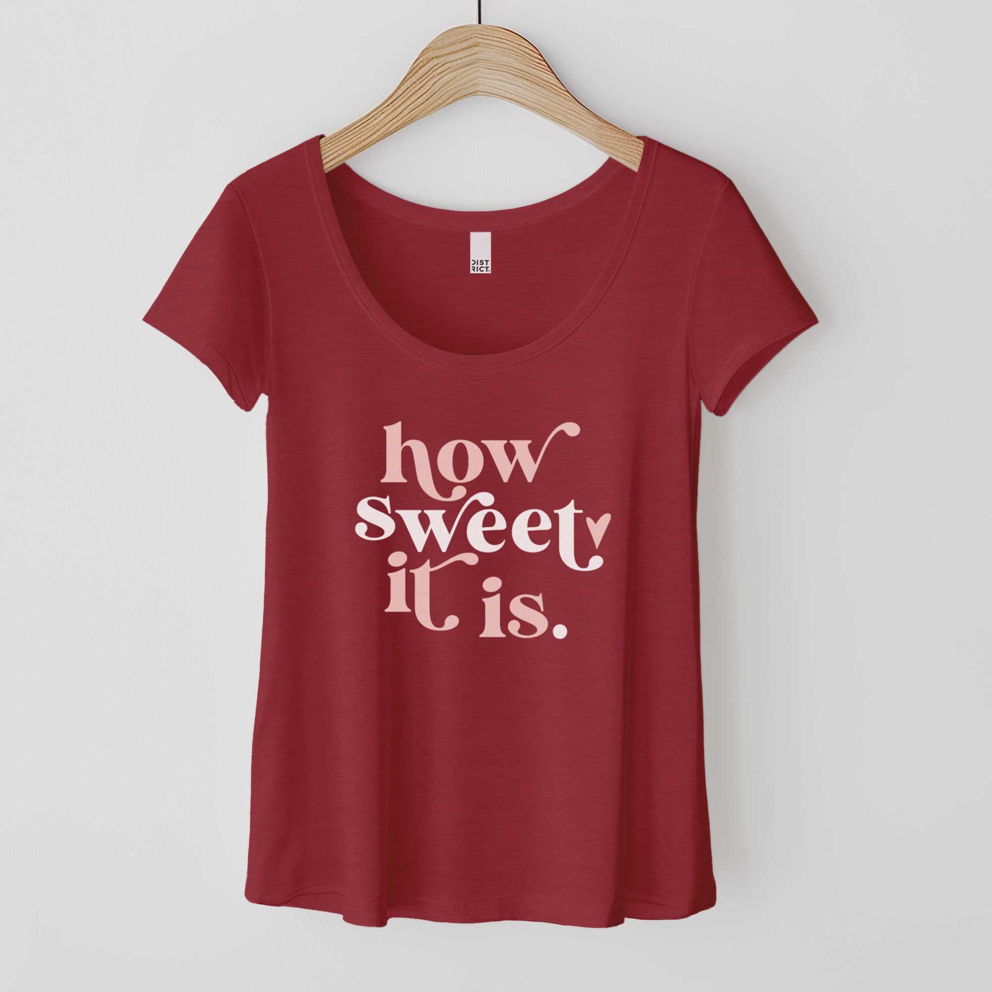 A hanging heathered red District scoop neck t-shirt featuring the words how sweet it is.