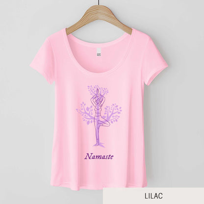 A hanging lilac District 7501 scoop neck t-shirt featuring a cartoon woman doing the tree pose in front of a tree silhouette and the words namaste below her.