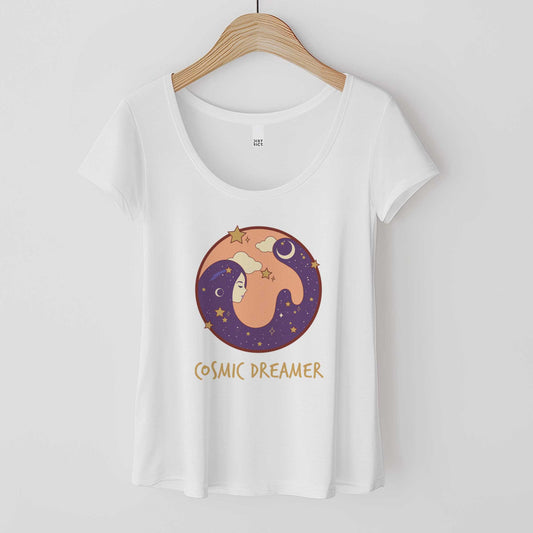 A hanging white District 7501 scoop neck t-shirt featuring a circle with a female face and hair that makes up the night sky and the words cosmic dreamer.