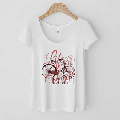 A hanging white District 7501 scoop neck t-shirt featuring a bicycle and the words life is all about balance.