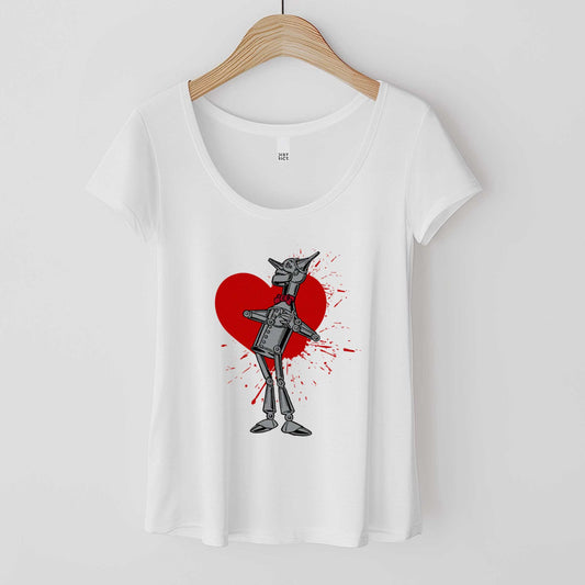 A hanging white District 7501 scoop neck t-shirt featuring a vintage Denslow illustration of the tin man from the Wizard of Oz with a heart symbol spattered behind him.