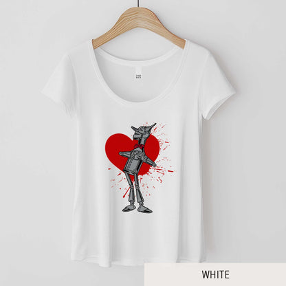 A hanging white District 7501 scoop neck t-shirt featuring a vintage Denslow illustration of the tin man from the Wizard of Oz with a heart symbol spattered behind him.