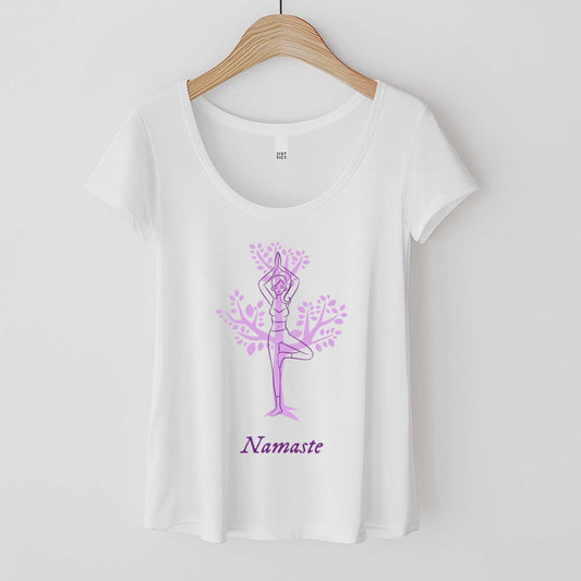 A hanging white District 7501 scoop neck t-shirt featuring a cartoon woman doing the tree pose in front of a tree silhouette and the words namaste below her.