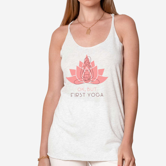 A woman wearing a heather white Next level triblend tank featuring a lotus in the background with a sketch of a woman in the lotus pose and the words ok, but first yoga.