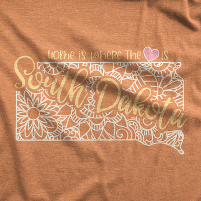 A heather autumn Bella Canvas swatch featuring a mandala in the shape of South Dakota with the words home is where the heart is.